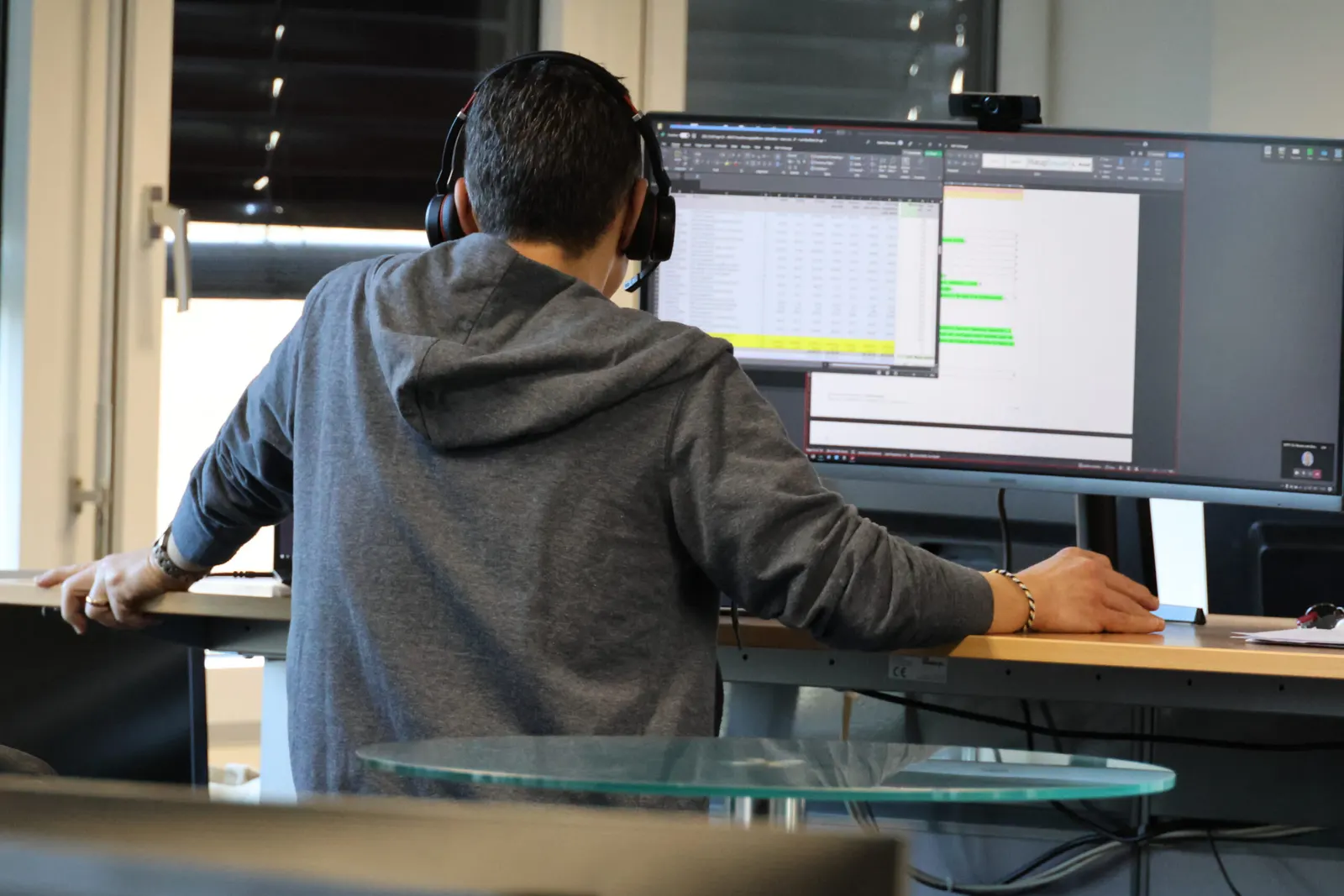 An engineer working at a standing desk with three monitors
